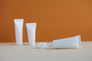 Hygiene cosmetic tubes on brown and beige background. Blank white opened plastic container, simple packaging design. shallow depth of field, copy space photography.