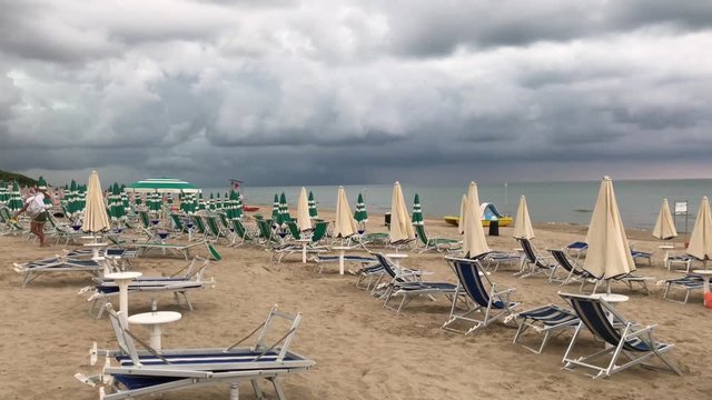 07 09 2018 Pineto, Abruzzo - thunderstorm approaching, man run away closing the parasol