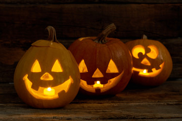 Funny Halloween pumpkins with burning candles. Glowing pumpkin lanterns on dark background. Halloween holiday greeting card.