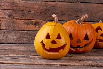 Funny Halloween pumpkins on rustic background. Carved pumpkins for Halloween on vintage wooden background.