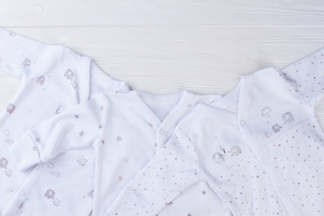 Obraz premium Collection of white baby pajamas on wood with copyspace.