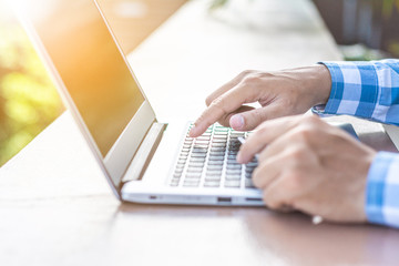 Man's hands holding a credit card and using laptop for online shopping.