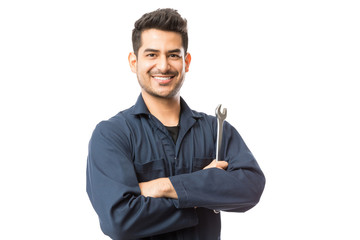 Fototapeta Mechanic With Wrench Standing Hands Folded On White Background obraz