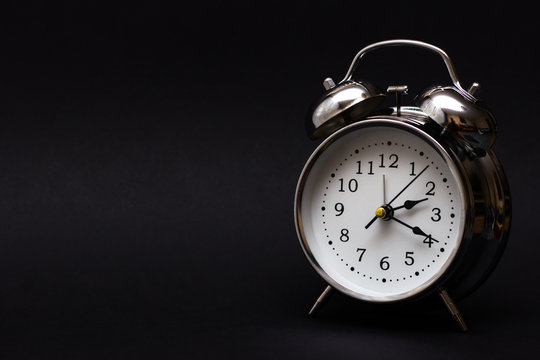 black retro alarm clock in dark background.For time concept.