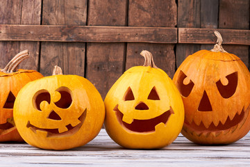 Halloween holiday pumpkins on wooden background. Orange autumn pumpkin Halloween holiday gourd jack o lantern faces.