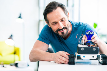 Waist up of a smiling bearded man testing his modern robot