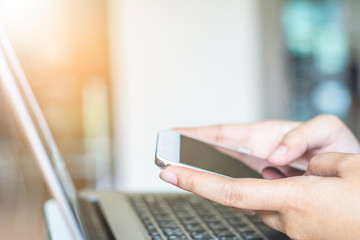 Man's hands holding a credit card and using laptop for online shopping.
