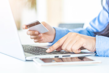 Fototapeta premium Man's hands holding a credit card and using laptop for online shopping.