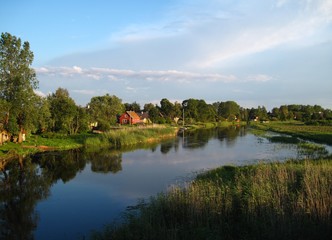 Fototapeta premium South Estonia riverside countryside view with a red wooden house
