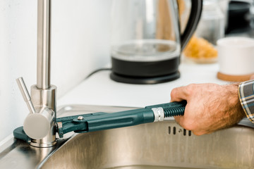 cropped image of plumber repairing tap with monkey wrench in kitchen