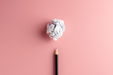 pencil and a crumpled paper ball on pink paper background. - Business concept, symbol of key point...