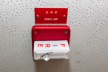 Red Fire alarm switch on the wall next to the door,Fire alarm switch.Break glass and pull down button to activate for warning and security system with hand and direction arrow,
