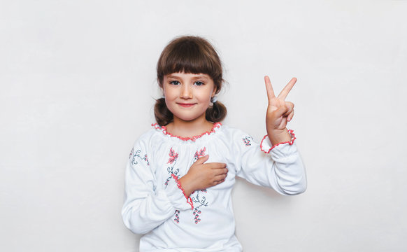Stop the war in Ukraine. Little Ukrainian Girl showing victopy sing with her hand. Patriot holds his hand on the heart. Peace concept. Copy space. Poster.