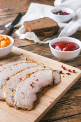 Pieces of smoked boiled pork on a wooden rustic Board with bread, sauces and spices on a wooden table