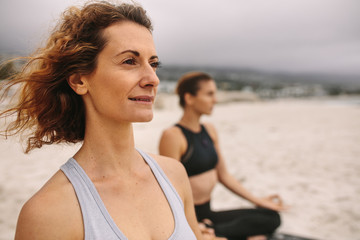 Fitness women doing yoga sitting on the beach