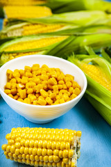 Raw and canned corn in a white bowl.