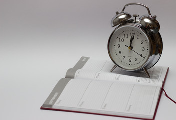 Notebooks and turquoise alarm clock on white background, time concept.
