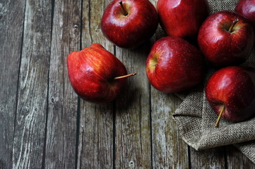 Fresh red apples on the wooden table with rustic sack