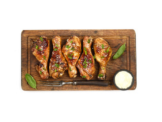 Roasted chicken drumsticks with sesame on a cutting board on a white background