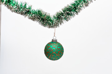 Christmas ornament concept. Ball with glamorous ornaments hang on shimmering green tinsel. Tinsel...
