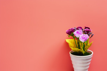 Artificial pink and purple rose bouquet in white flower pot on pink background for love and Valentine's day concept