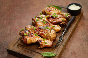Roasted chicken drumsticks with sesame on a cutting board on a wooden background