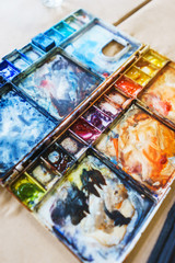 Spots of watercolor paint on a plastic palette.  Hobbies and education, a cuvette with different watercolors. 