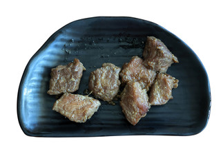 Hot pieces of grilled meats on a black dishisolated on white background. Top view shot.