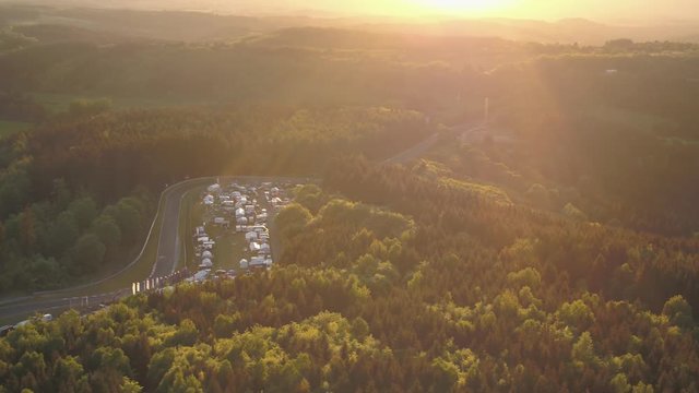N&uuml;rburgring Drone moving left overview car race arena german landscape trailerpark Eiffel forrest sunny clear sky
