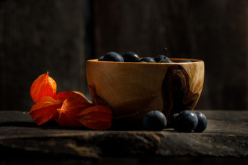 Berries of plum in a wooden bowl. Ornament from berries of Physalis.