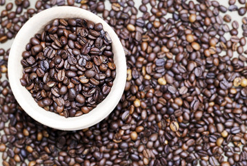 Coffee beans in a wooden cup. Coffee beans are scattered all over the city, close-up.