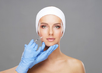 Doctor injecting in a beautiful face of a young woman. Plastic surgery concept.
