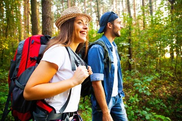 Tough route. Beautiful young couple hiking together in the woods while enjoying their journey.