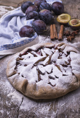 Delicious fragrant homemade baked pie with plums on a wooden table.