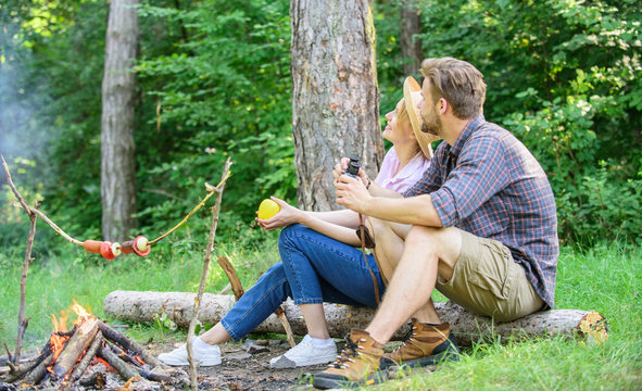 Couple relaxing sit on log having snacks. Hike picnic date. Family enjoy romantic weekend in nature. Pleasant picnic or romantic date nature background. Couple romantic date near bonfire in forest