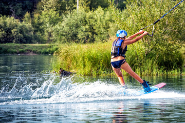 Girl wakeboarding on river lake sea on summer spring day in jacket