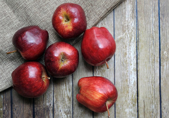A group of fresh red apple on the wooden table with vintage sack