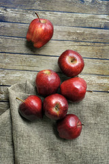 A group of fresh red apple on the wooden table with vintage sack