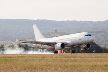White passenger plane is landing on the airport. Touchdown with tire smoke
