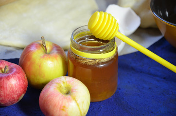 Various ingredients for winter seasonal baking and other recipes, honey, apples, herbs and spices on a dark blue background. Top view.