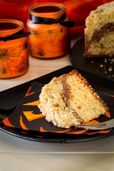 Coffee crumble cake decorate Halloween concept. Black plate and orange candle. Selective focus.