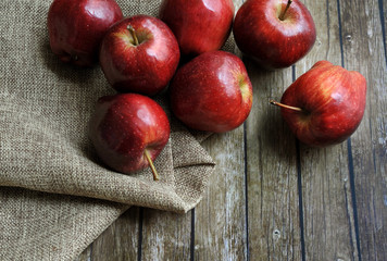 A group of fresh red apple on the wooden table with vintage sack
