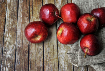A group of fresh red apple on the wooden table with vintage sack