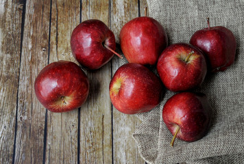 A group of fresh red apple on the wooden table with vintage sack