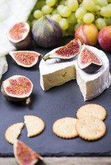 Homemade cookies cracker, soft cheese, figs, grape on a black board.