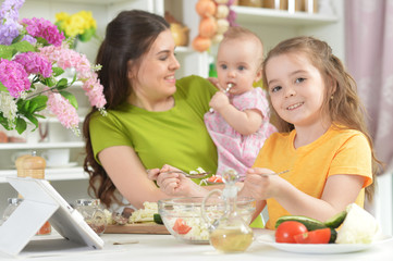 Cute little girl eating fresh salad at kitchen table