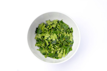 Kaffir lime leaves in a white bowl top view isolated on white background.