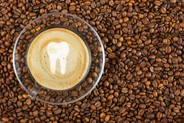 Cup of espresso with tooth sign on coffee foam on coffee beans background. With copy space