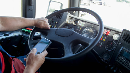Closeup photo of male driver holding smartphone while driving bus