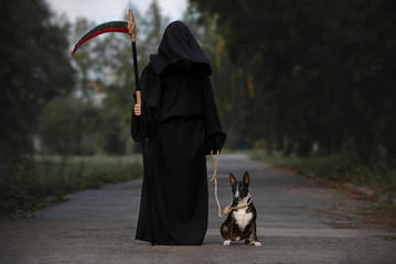 dog owner dressed as death posing for Halloween with a bull terrier